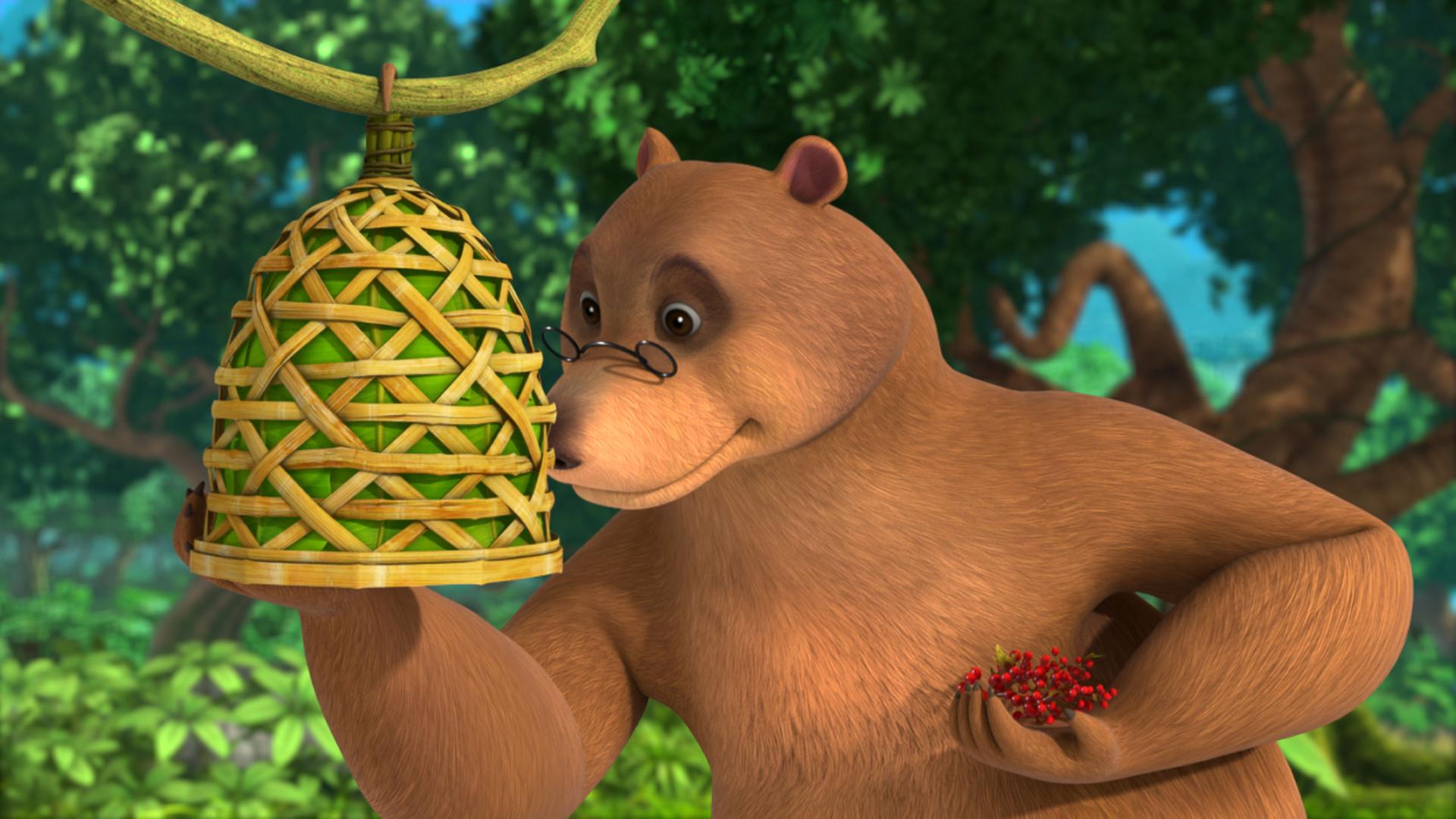 Balu sieht seinen selbstgebastelten Vogelkäfig an. In der linken Hand hält er rote Beeren.