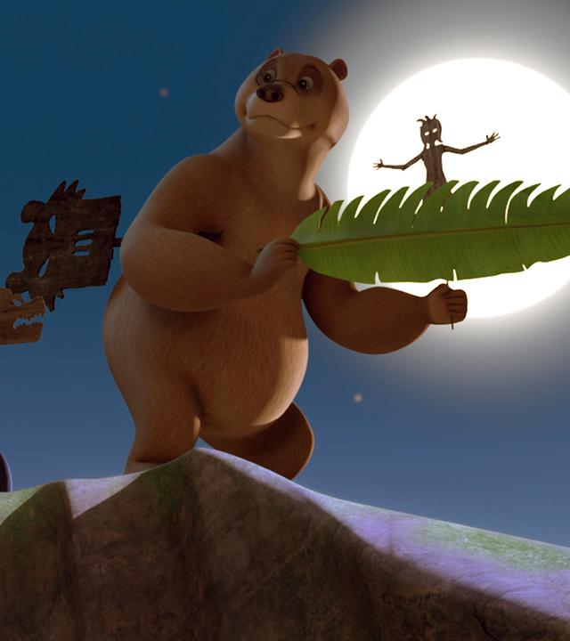 Baghira hält eine Holzfigur im Mund. Balu hat eine Figur unter den rechten Arm geklemmt und hält mit beiden Vorderpfoten ein Bananenblatt und eine Figur fest. Hinter ihm scheint der Vollmond.