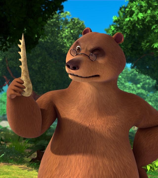 Balu hält den Knochenkamm in der rechten Hand und betrachtet ihn kritisch. Kaa sieht den Kamm auch an.