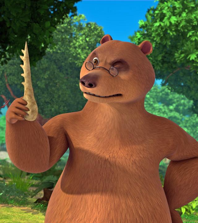 Balu hält den Knochenkamm in der rechten Hand und betrachtet ihn kritisch. Kaa sieht den Kamm auch an.