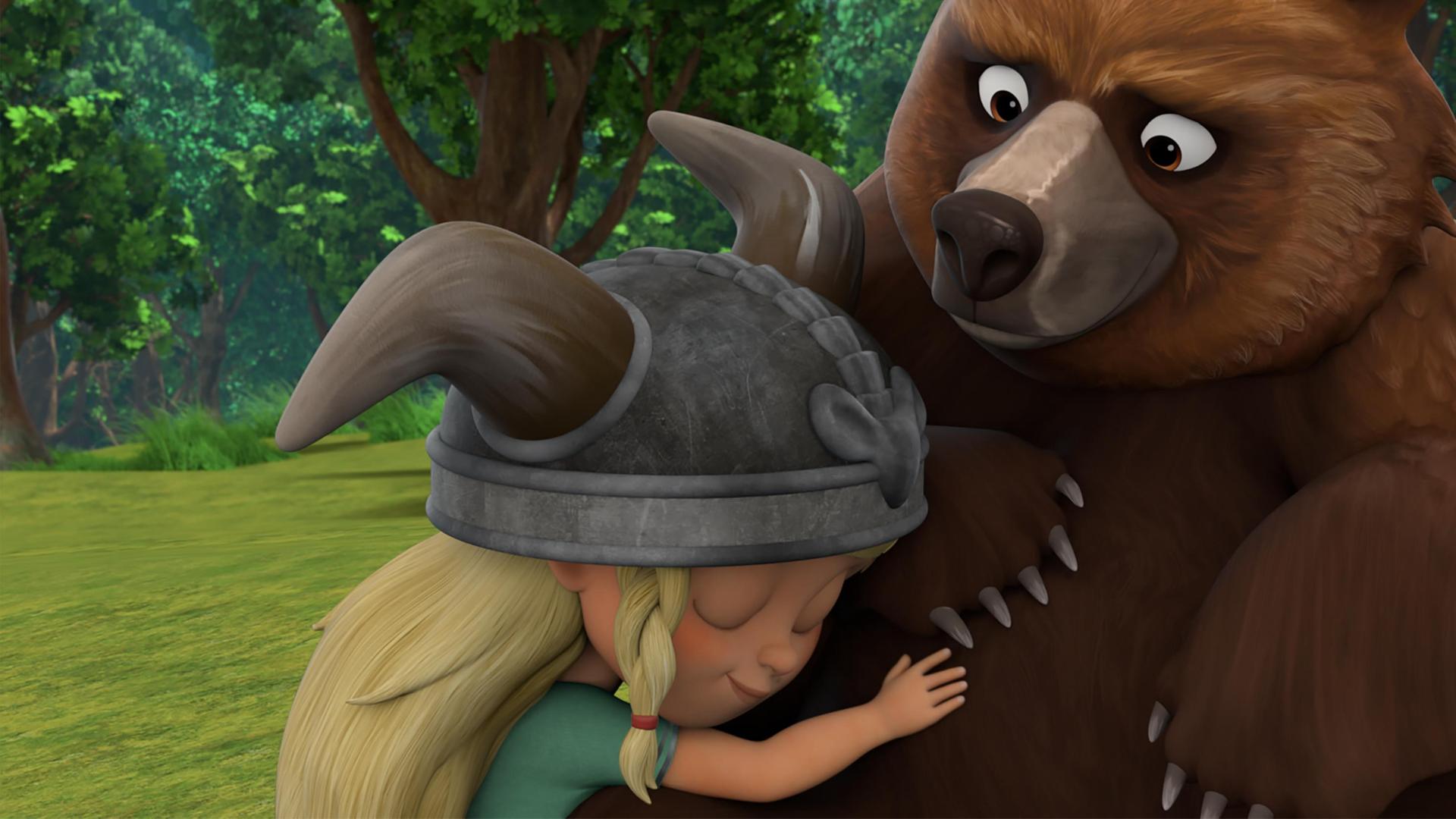 Auf einer Lichtung im Wald schmiegt sich die kleine Wikingerin Solveig liebevoll an den großen, braunen Bär Geri.