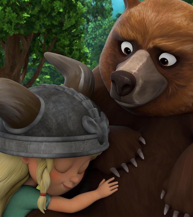 Auf einer Lichtung im Wald schmiegt sich die kleine Wikingerin Solveig liebevoll an den großen, braunen Bär Geri.