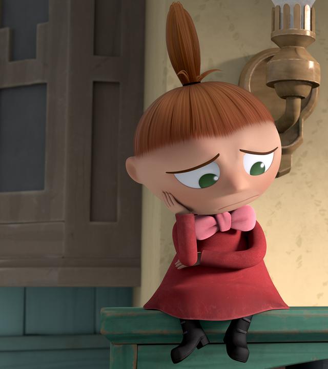 Die Kleine Mü sitzt allein auf einem Regal. Sie stützt ihren Kopf mit ihrer Hand und sieht sehr traurig aus.