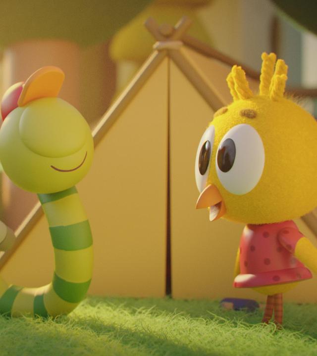 Auf einer Wiese vor einem Zelt stehen Glitsch, der Wurm, und Karla, das Küken. Karla blickt freudig zu Glitsch herüber. Neben Glitsch liegt eine Luftmatratze auf der Wiese. Zudem hält er stolz eine Taschenlampe mit seinem hinteren Körperende fest.