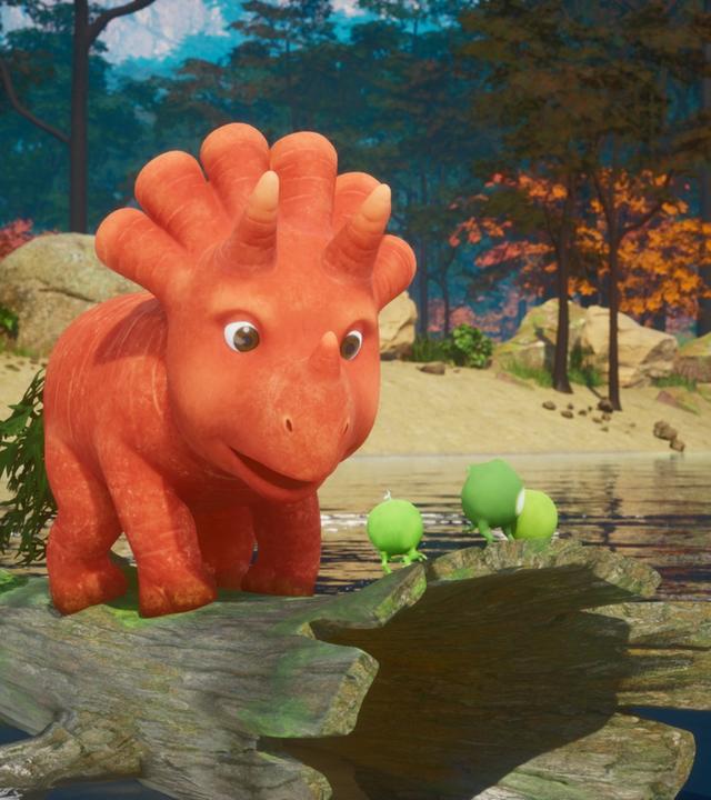 Das Trikarottops-Mädchen Ginger (eine Karotte, die aussieht wie ein Dinosaurier) steht auf einem hohlen Baumstamm und treibt auf einem See. Ganz vorne auf dem Baumstamm stehen die drei Erbs-Rexe. (Erbs-Rexe sind Erbsen, die aussehen wie Dinosaurier mit kleinen Ärmchen und Beinchen.) Im Hintergrund ist das Ufer des Sees zu sehen und viele Bäume und Sträucher mit orangefarbenen Blättern.