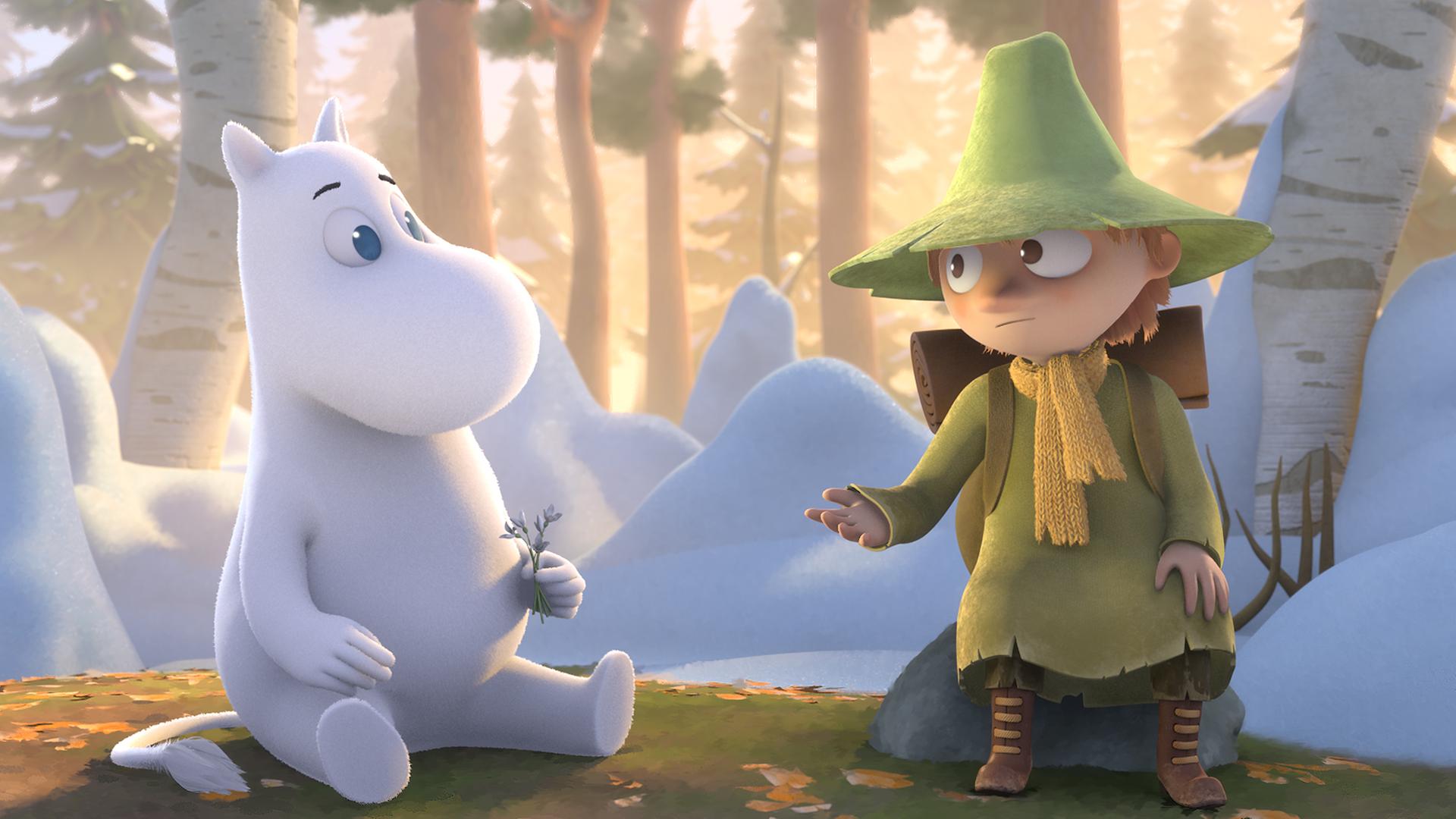 Mumin sitzt zusammen mit Snufkin auf dem Waldboden. Er hält eine kleine Blume in der Hand.