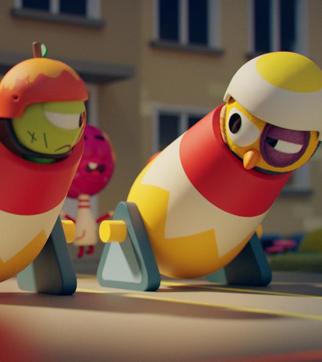 Wurm Glitsch und Küken Karla befinden sich in jeweils einer Kanone nebeneinander, die bereit für den Abschuss stehen. Beide tragen Helme und schauen entschlossen zueinander. Karla hat ein blaues Auge und Glitsch eine Narbe auf seiner Wange. Im Hintergrund hüpft Bowlingkugel Strike in die Luft und feuert die beiden an. Links hinten wartet Roboter Robbie an der Kanone. Er ist bereit, sie abzufeuern.