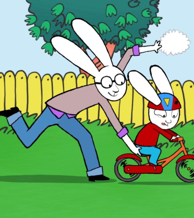 Simon, mit einem Fahrradhelm auf dem Kopf, fährt hastig mit seinem Fahrrad durch den Garten. Papa hält das Fahrrad am Sitz fest und läuft gemeinsam mit Simon durch den Garten.