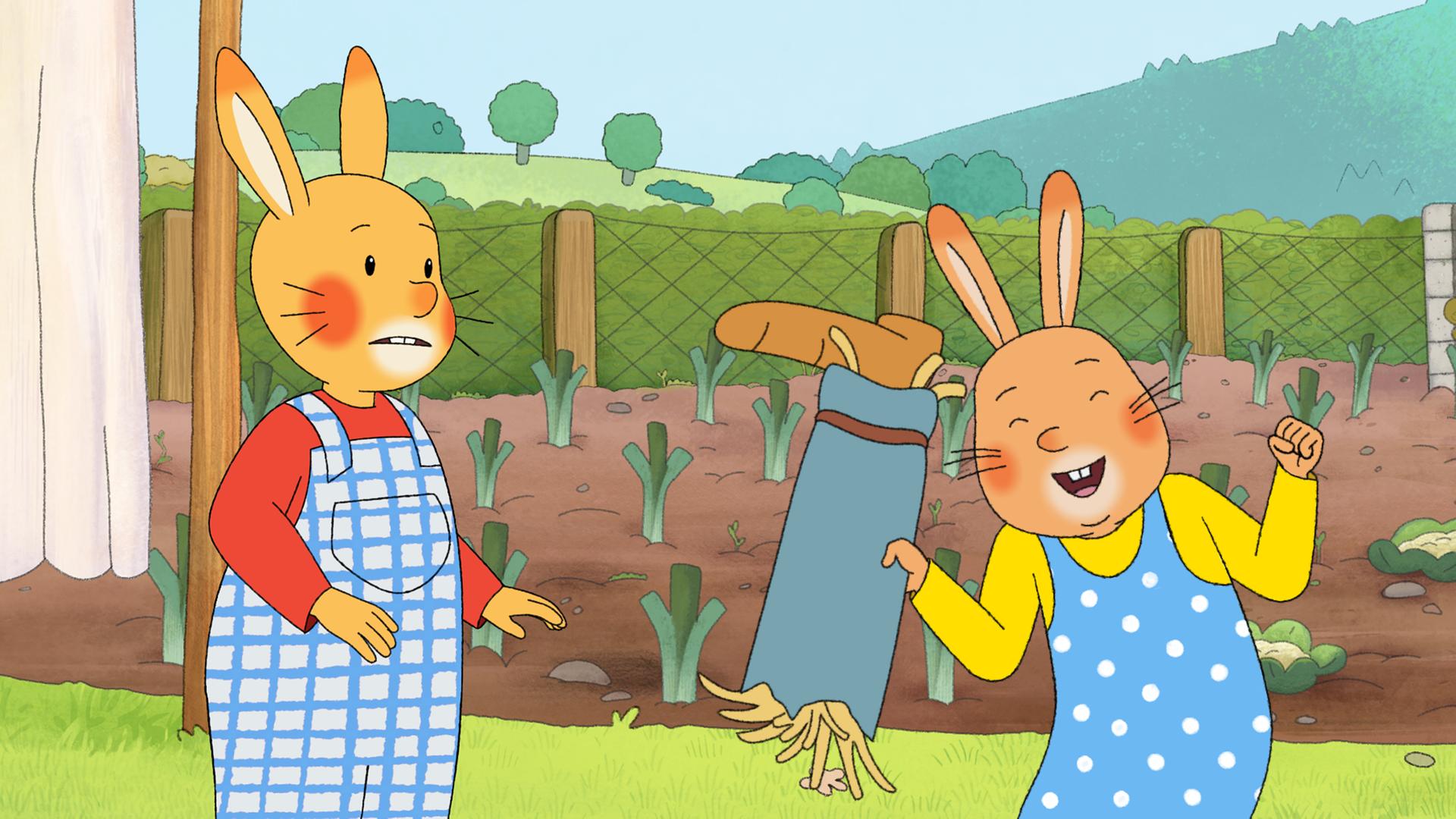 Karlchen und Monika sind im Garten.  Monika hält ein mit Stroh ausgestopftes Hosenbein in der Hand und jubelt. Karlchen schaut sie entgeistert an.