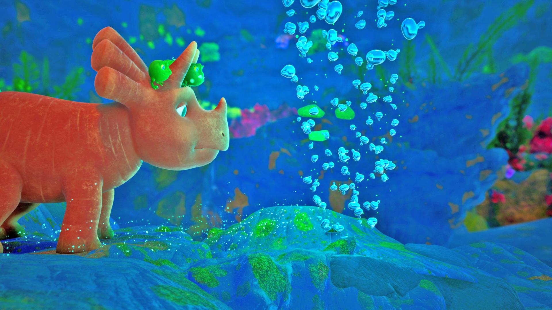 Ginger ist ein Dinosaurier-Mädchen, das einer Karotte ähnelt. Sie steht unter Wasser auf dem Grund eines tiefblauen Sees und betrachtet ein Loch, aus dem Blubberbläschen aufsteigen.