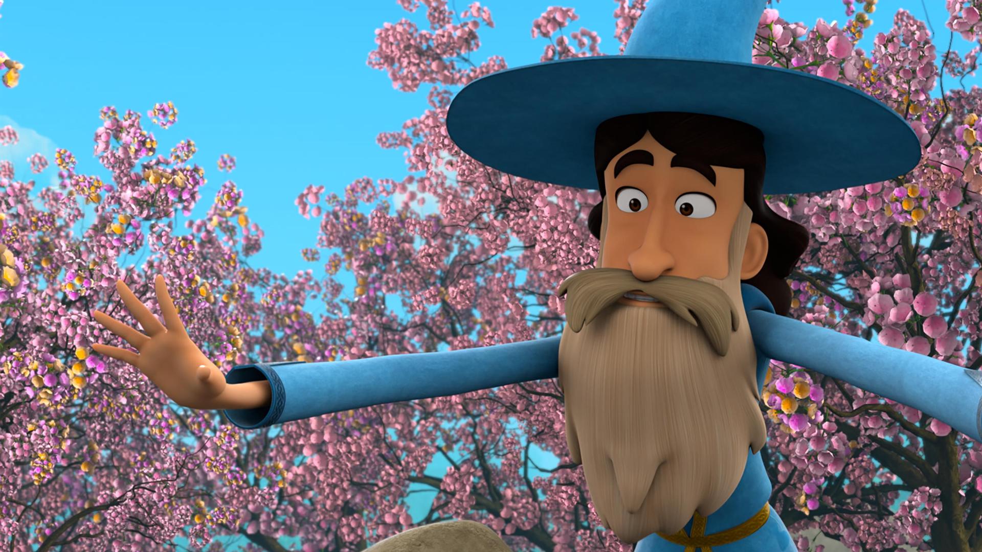 Ein Mann mit dunklem Haar und hellem, langen Bart und Schnurrbart in der blau-goldfarbenen Kleidung von Merlin und dessen Zauberhut, beugt sich mit weit ausgebreiteten Armen zu etwas hinab. Hinter ihm sind Obstbäume, die in voller, rosafarbener Blüte stehen.