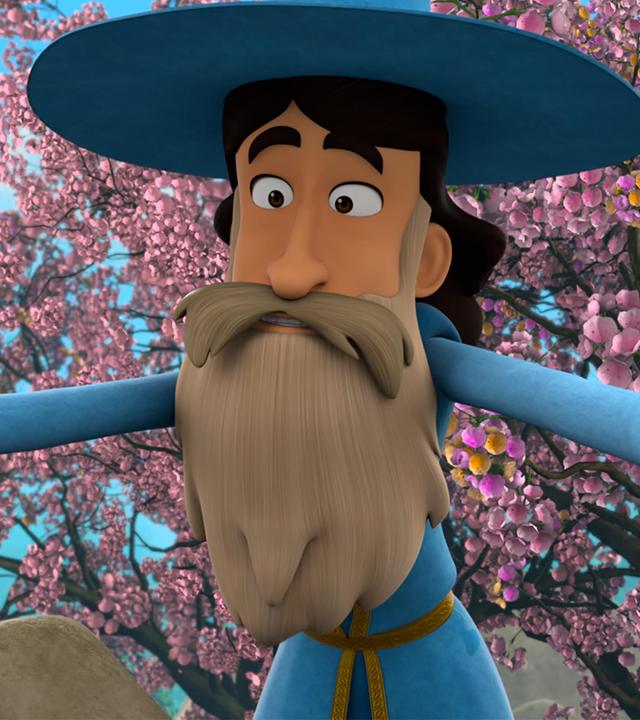 Ein Mann mit dunklem Haar und hellem, langen Bart und Schnurrbart in der blau-goldfarbenen Kleidung von Merlin und dessen Zauberhut, beugt sich mit weit ausgebreiteten Armen zu etwas hinab. Hinter ihm sind Obstbäume, die in voller, rosafarbener Blüte stehen.