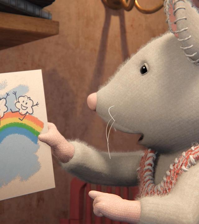 Julia hält ein selbst gemaltes Bild hoch, auf dem ein Regenbogen zu sehen ist, über dem zwei Wolken fröhlich tanzen. Sie schaut das Bild nachdenklich an.