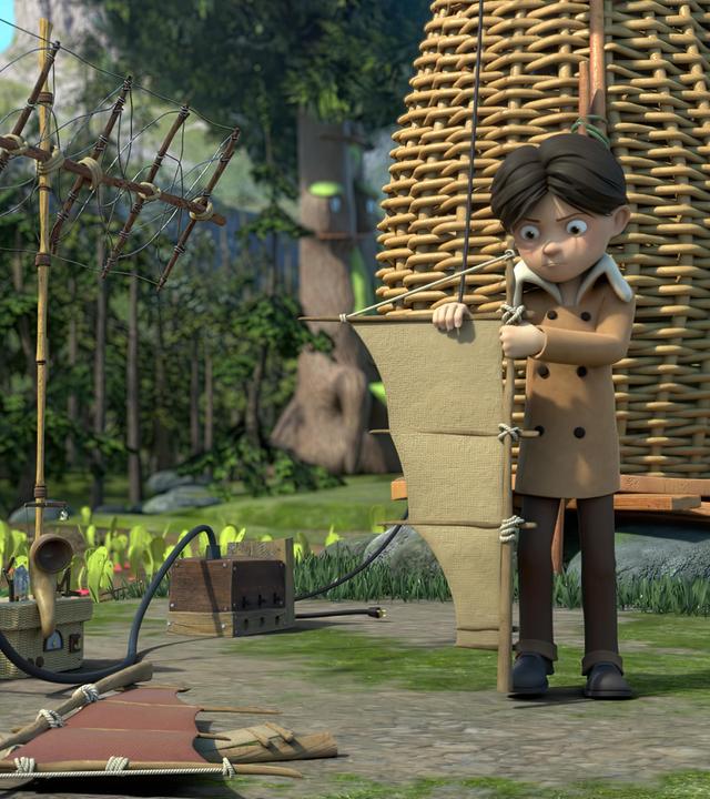 Klincus steht kritisch blickend vor seiner Scheune und bastelt an einem Flügel einer Windturbine herum. Vor ihm liegen weitere Bauteile auf dem Boden. Im Hintergrund steht auch der Stromgenerator, der mit einem Pedal angetrieben werden kann.