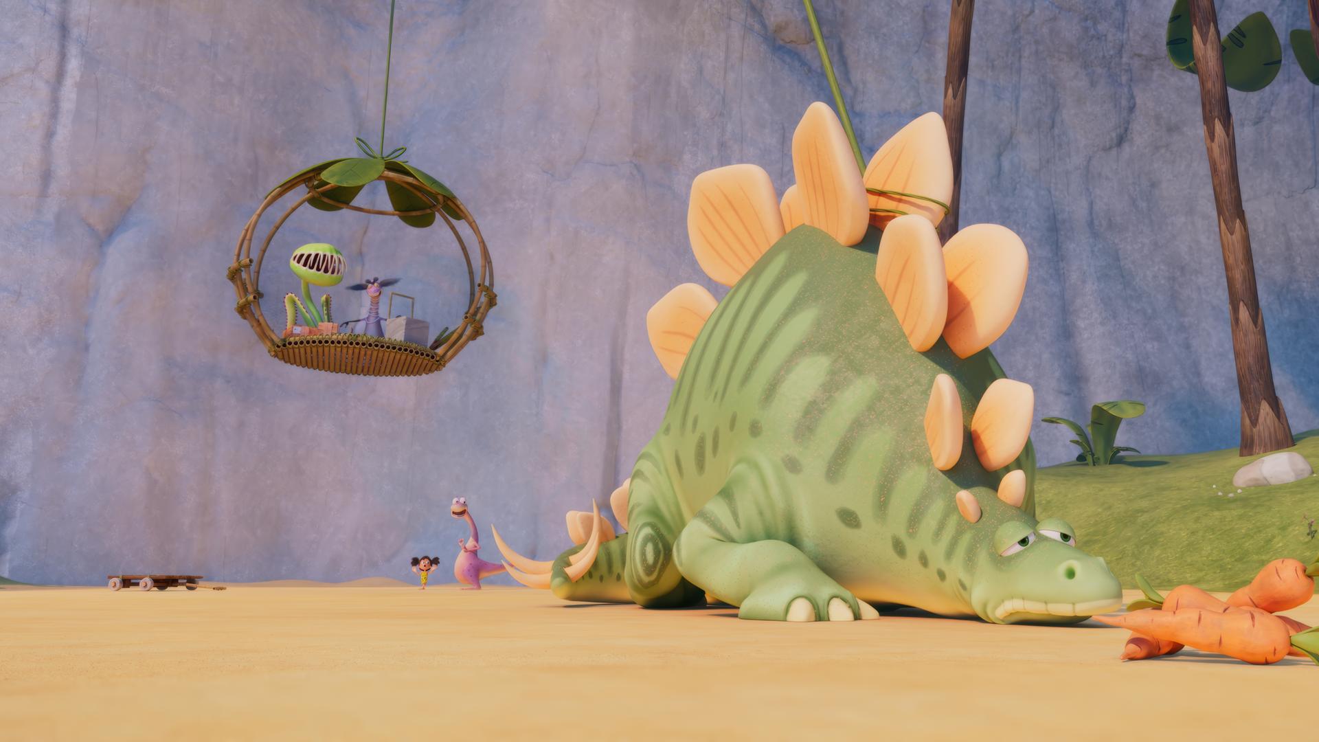 Ein riesiger, grüner Saurier mit beigen Stegplatten liegt traurig im Sand. Vor ihm liegen Karotten. Mit einem Seil ist er mit einer Aufzugskabine verbunden, die im Hintergrund etwas über dem Boden schwebt. Im Aufzug sieht man ganz klein die Fleisch-fressende Pflanze Venus und Frau Krätzig.