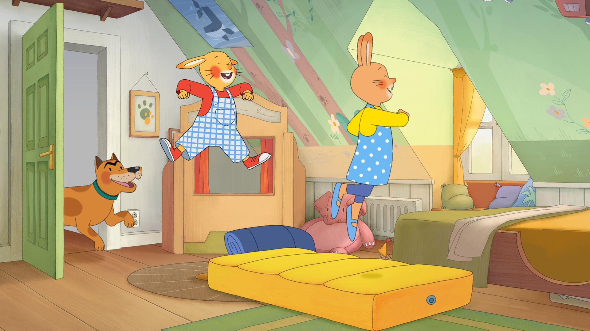 Wir sehen Monikas Kinderzimmer. Auf dem Boden liegt eine gelbe Luftmatratze, auf der Karlchen und Monika herumhüpfen. Bello, der Hund, kommt zur Tür herein. Alle machen lachende Gesichter und freuen sich.