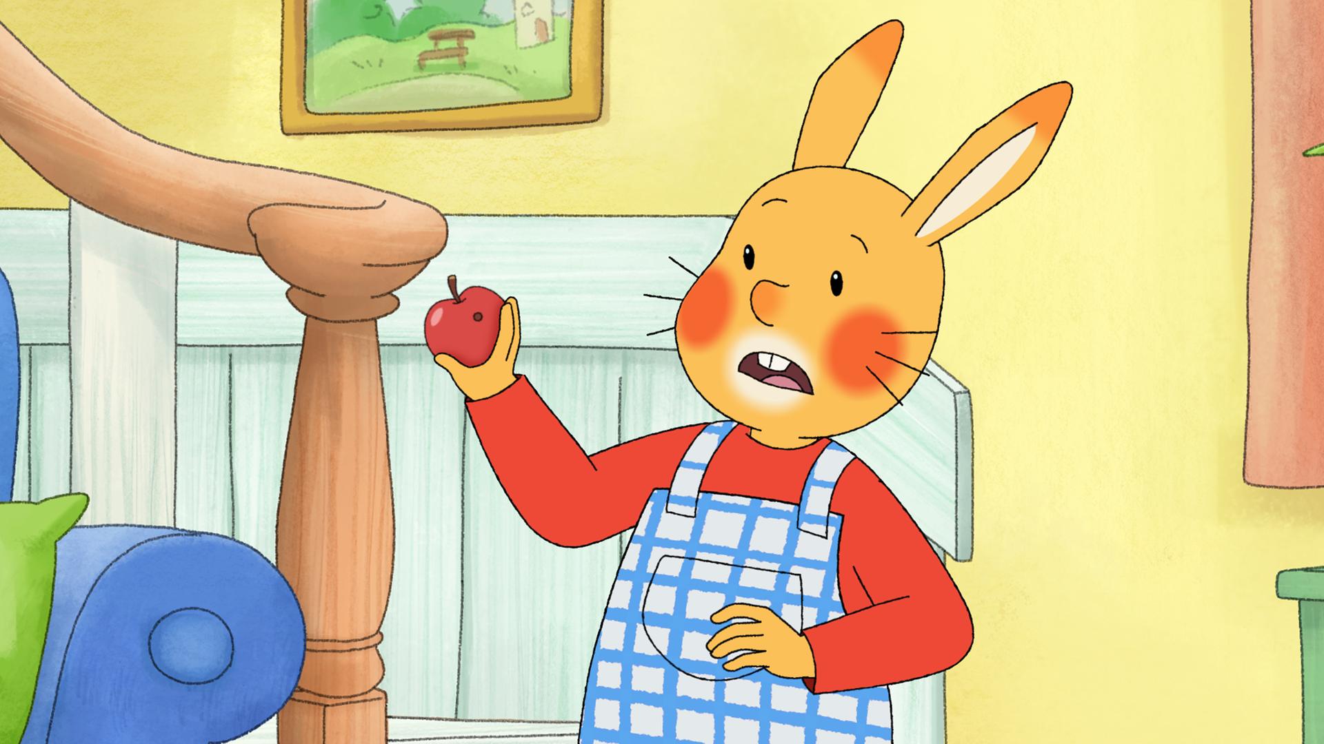 Karlchen steht im Wohnzimmer und hält einen Apfel in der Hand. Er macht ein erschrockenes Gesicht, denn im Apfel ist ein Wurmloch!