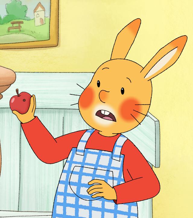 Karlchen steht im Wohnzimmer und hält einen Apfel in der Hand. Er macht ein erschrockenes Gesicht, denn im Apfel ist ein Wurmloch!