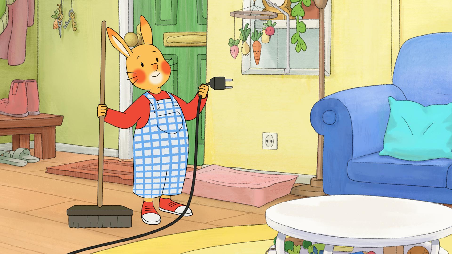 Karlchen steht im Wohnzimmer, er hat einen Stecker mit Kabel aus der Steckdose gezogen und hält ihn in der Hand. In der anderen Hand hält er einen Besen.