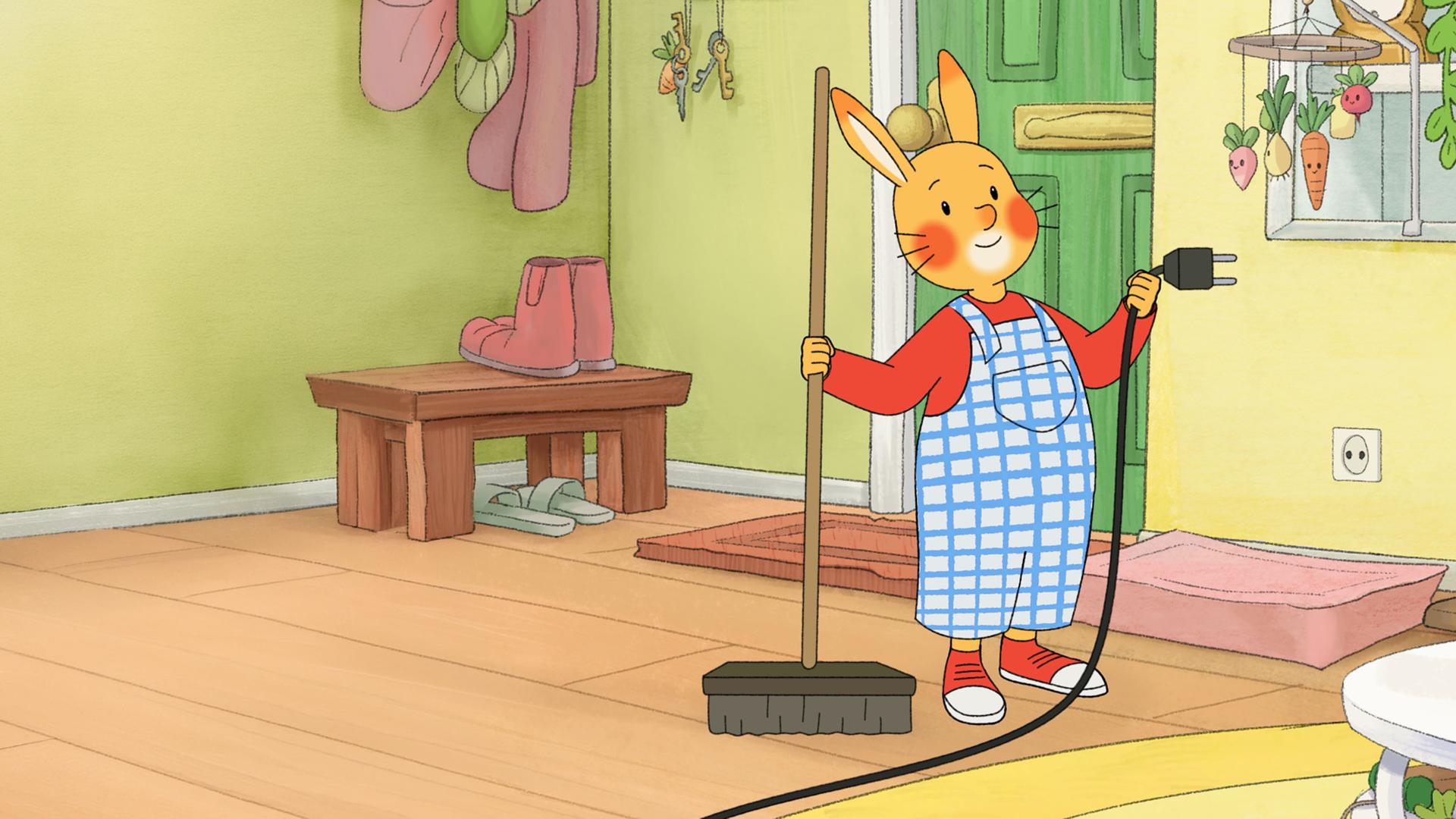 Karlchen steht im Wohnzimmer, er hat einen Stecker mit Kabel aus der Steckdose gezogen und hält ihn in der Hand. In der anderen Hand hält er einen Besen.