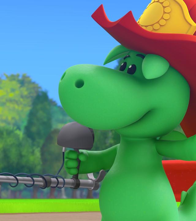 Der kleine Drache Grisu trägt einen roten Feuerwehrhelm. In der Hand hält er einen Metalldetektor. Stella steht daneben und betrachtet das Gerät mit großen Augen.