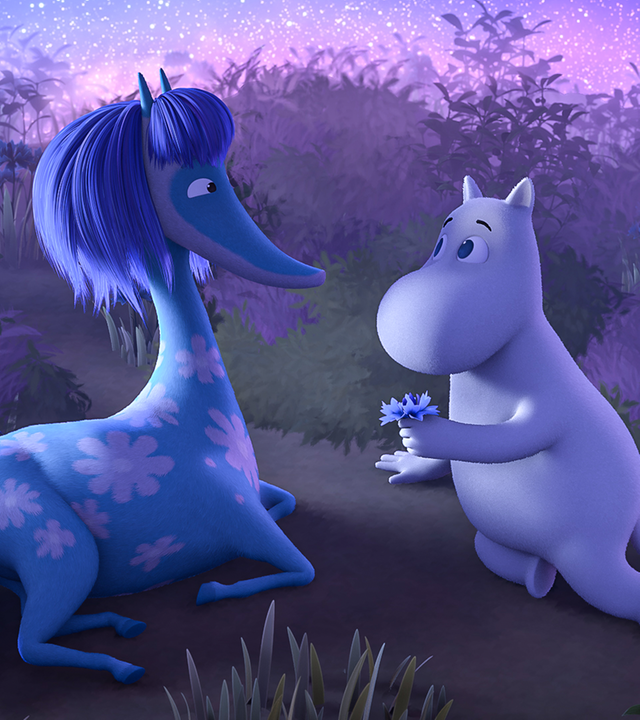 Mumintroll und ein blaues Seepferdchen mit rosafarbenem Blumenmuster liegen auf einer Wiese. Mumintroll überreicht dem Seepferdchen eine kleine blaue Blume.