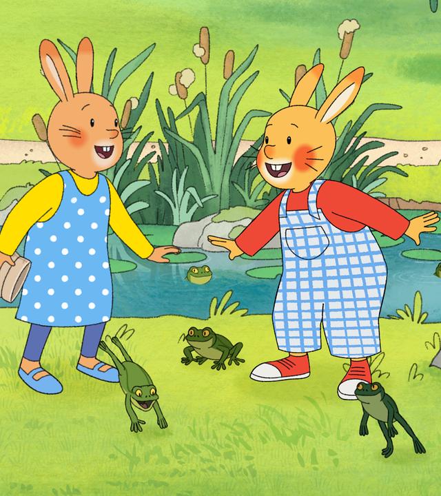 Vor einem Froschteich stehen Monika und Karlchen und lachen sich an. Um sie herum hüpfen viele grüne Frösche. Auch Perlhuhn steht dabei. 