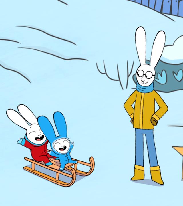 Mama, Papa, Simon und Franz befinden sich draußen im Schnee. Simon und Franz sitzen gemeinsam auf einem Schlitten und freuen sich riesig. Mama und Papa schauen die beiden liebevoll an. Neben Papa steht ein Karton mit Feuerwerksraketen im Schnee.