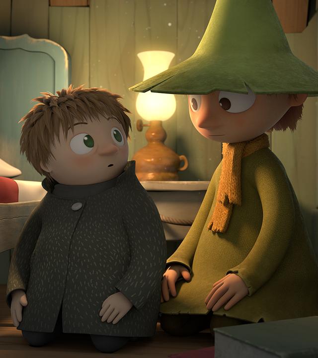 Snufkin (mittig rechts) und der kleine Troll Toffel (mittig links) sitzen auf dem Zimmerboden neben einem Bett und schauen sich ratlos an.