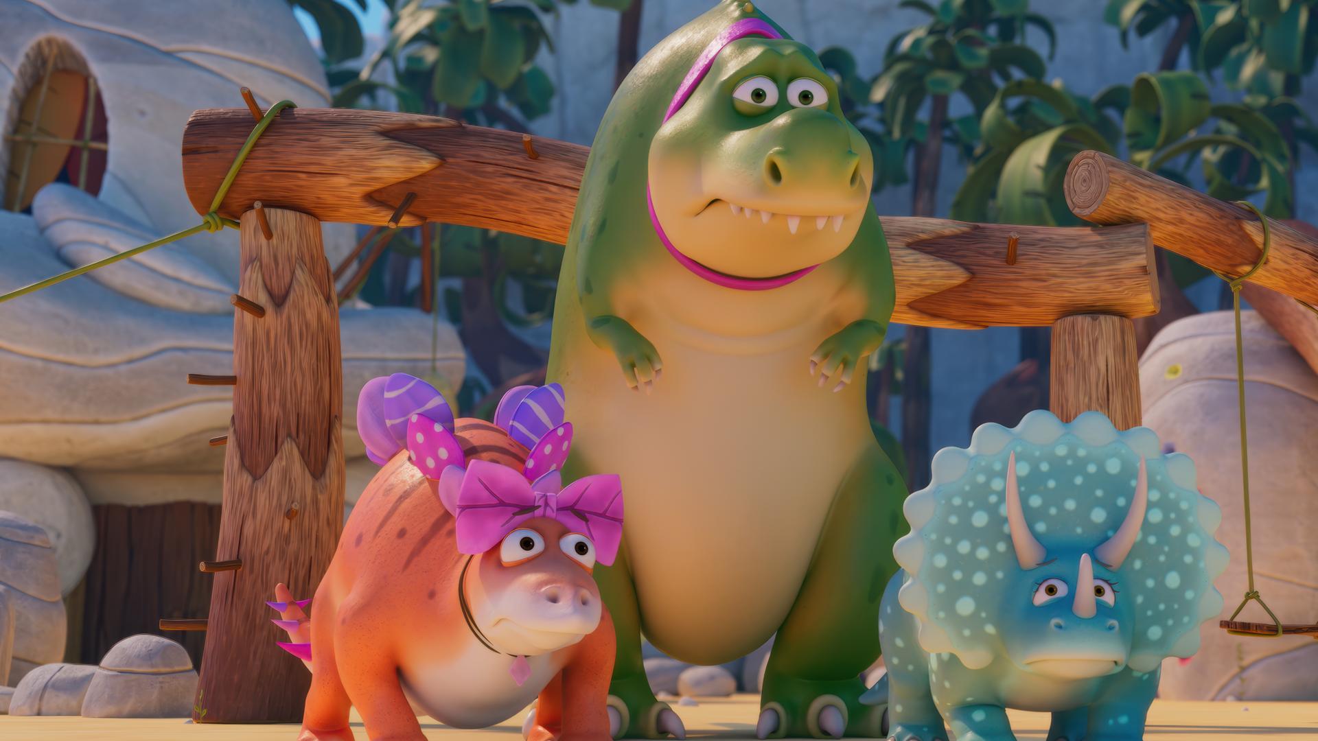 Die Haustier-Dinosaurier Stiggi, Rexie und Topsi stehen auf dem Spielplatz und machen besorgte Gesichter. Rexie ist ein großer, grüner T-Rex mit pink Halsband. Stiggi ist ein orangefarbener Stegosaurus mit rosa und pink Schleifen und Topsi ist ein türkisfarbener Triceratops.