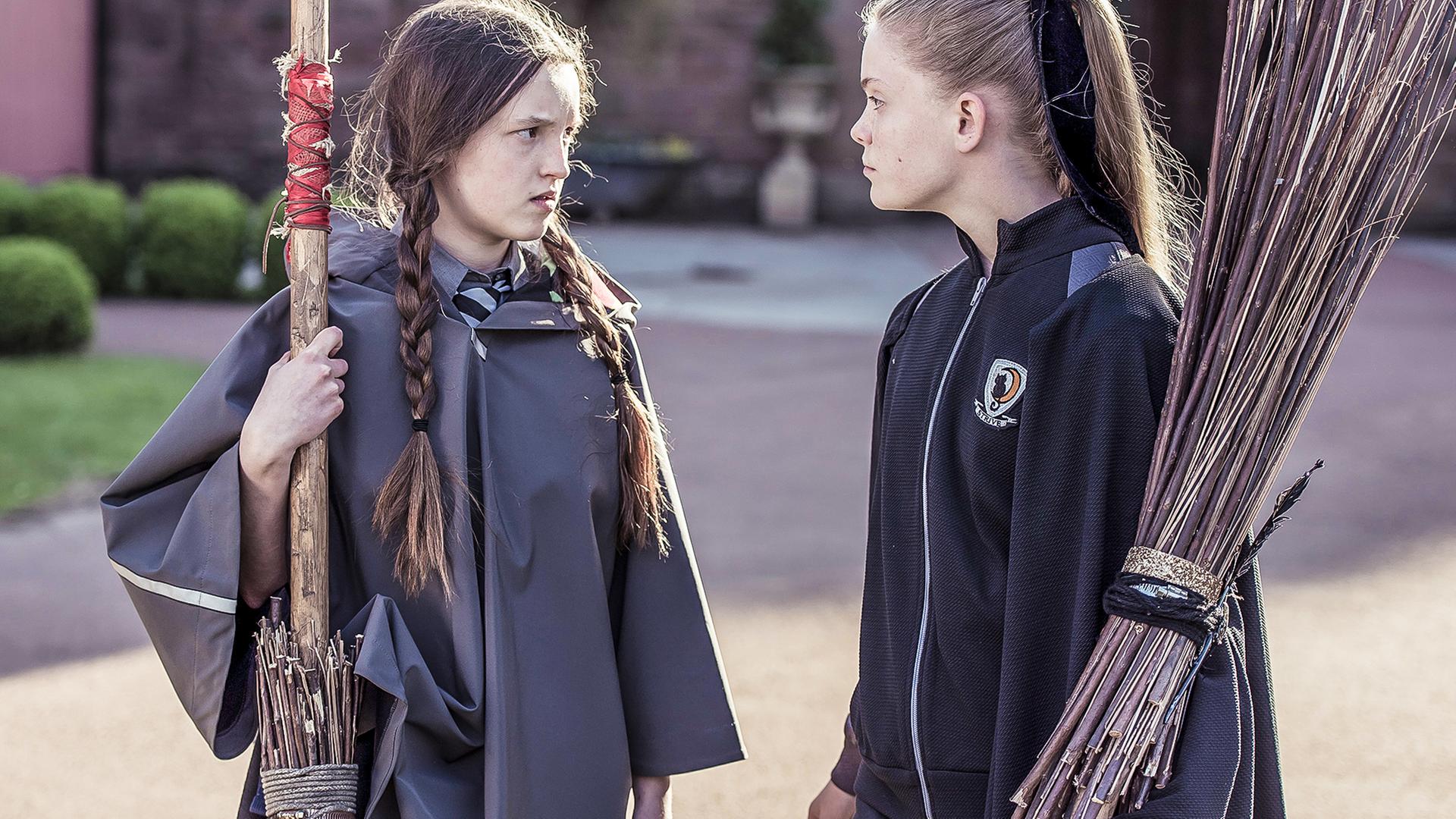 Mildred und Esther haben beide ihren Besen in der Hand und schauen sich an.