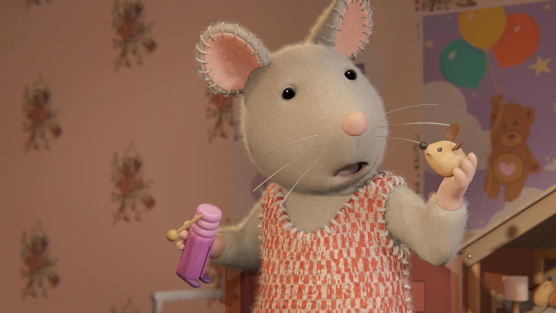 Julia steht in einem Kinderzimmer vor einem Puppen-Mäusehaus. Sie hält in der rechten Hand einen Puppenkörper, in der linken Hand den Kopf der Mauspuppe und schaut erschrocken zu dem Kopf.