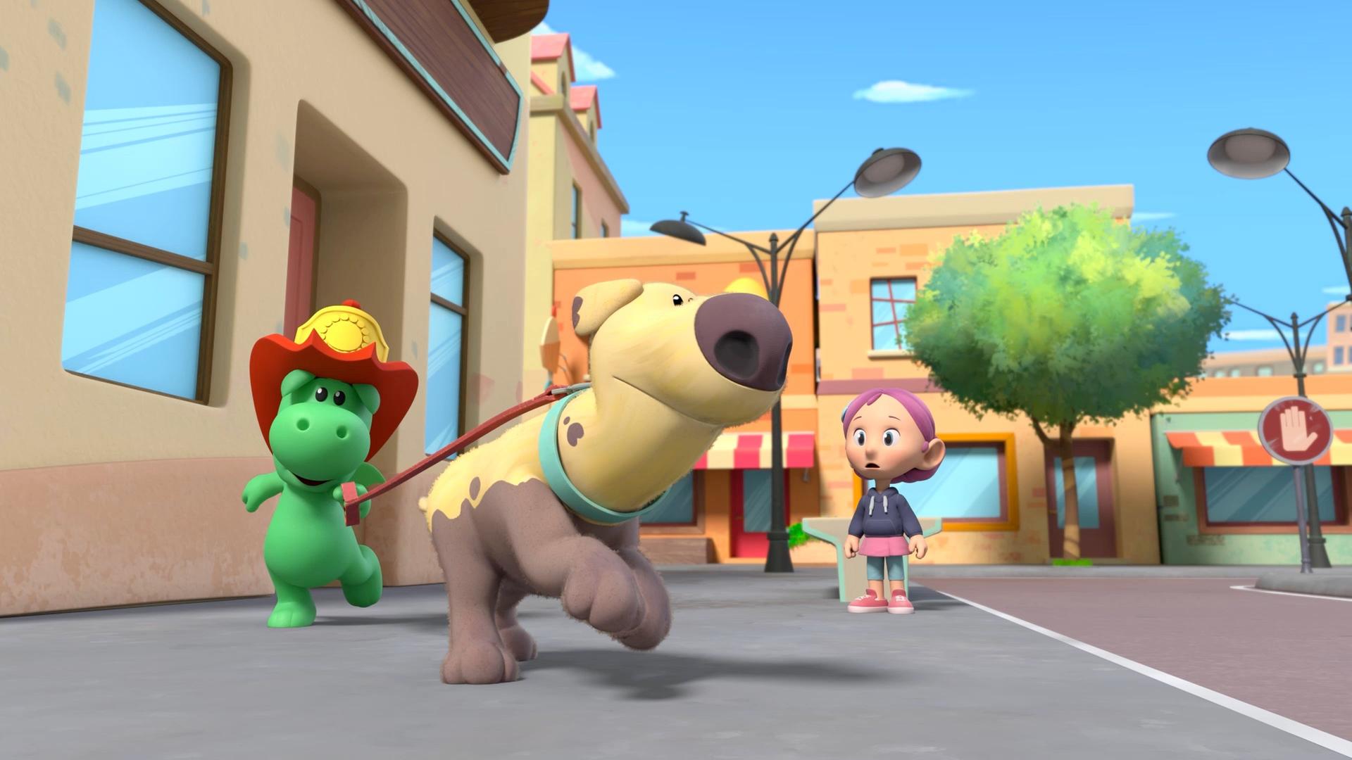 Grisu, der kleine grüne Drache mit dem roten Feuerwehrhelm, hat den Hund Dinki an der Leine. Beide rennen sie durch eine Straße von Drachenstadt. Etwas abseits beobachtet sie dabei Stella.