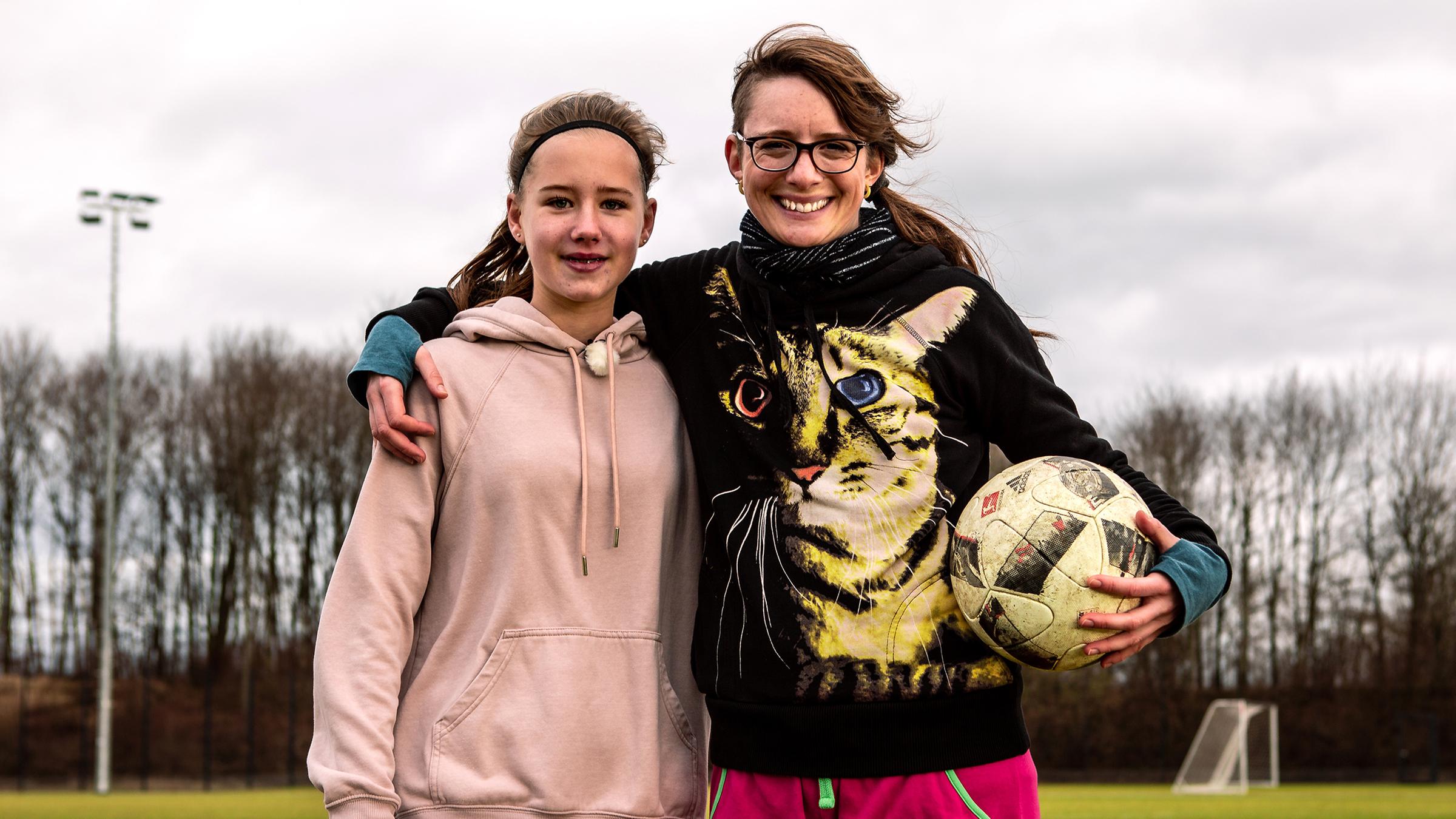 Die Princess of Science Johanna (re.) steht neben einer Sportlerin (li.) in der Sporthalle. In den Händen halten sie Stäbe für den Stabhochsprung.