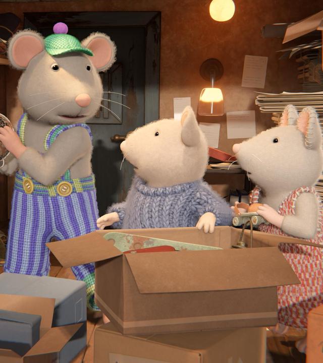 Sam und Julia stehen vor einem großen, aufgeklappten Karton und schauen von der Seite auf Onkel Lumpi, der im Keller ein Sieb in eine Kiste räumt.