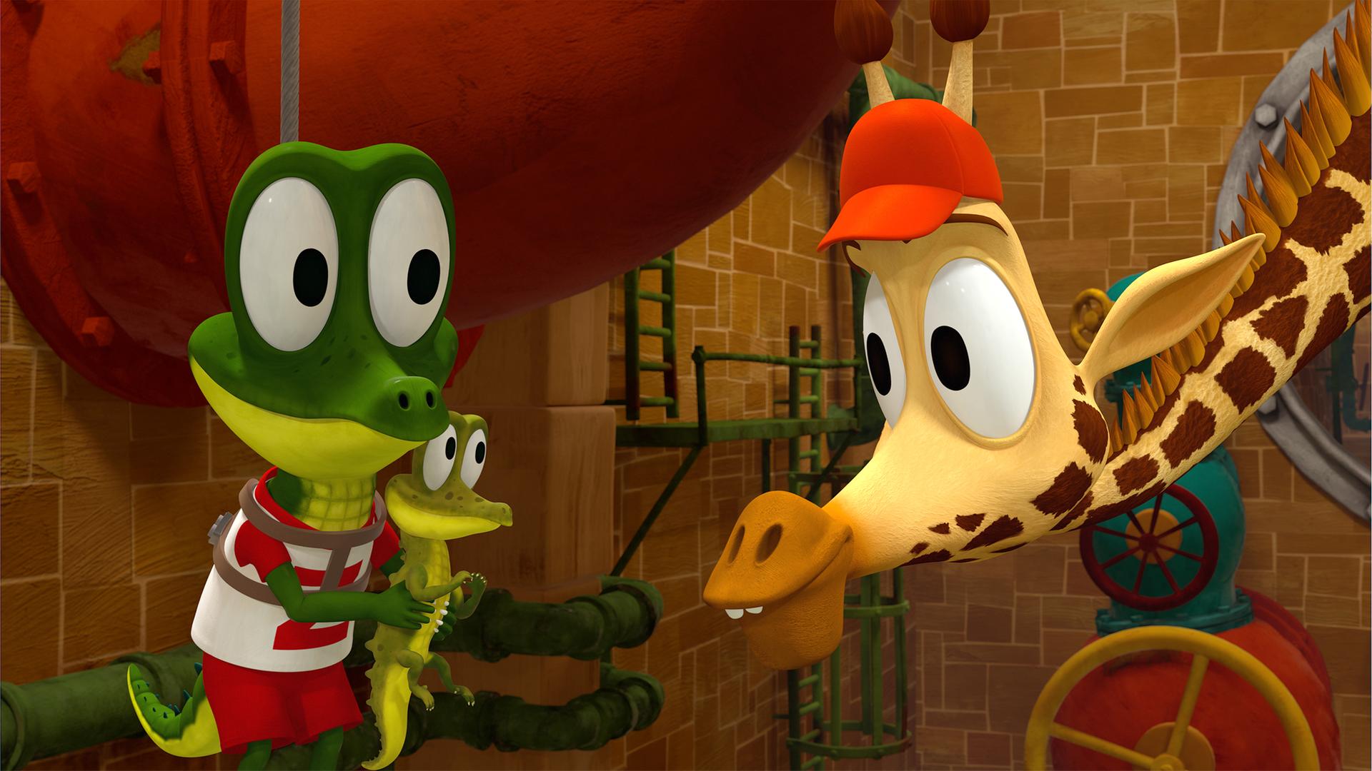 Krokodil Zacki hält ein ganz kleines Krokodil in seinen Händen, welches Giraffe Bruno freudig begutachtet.