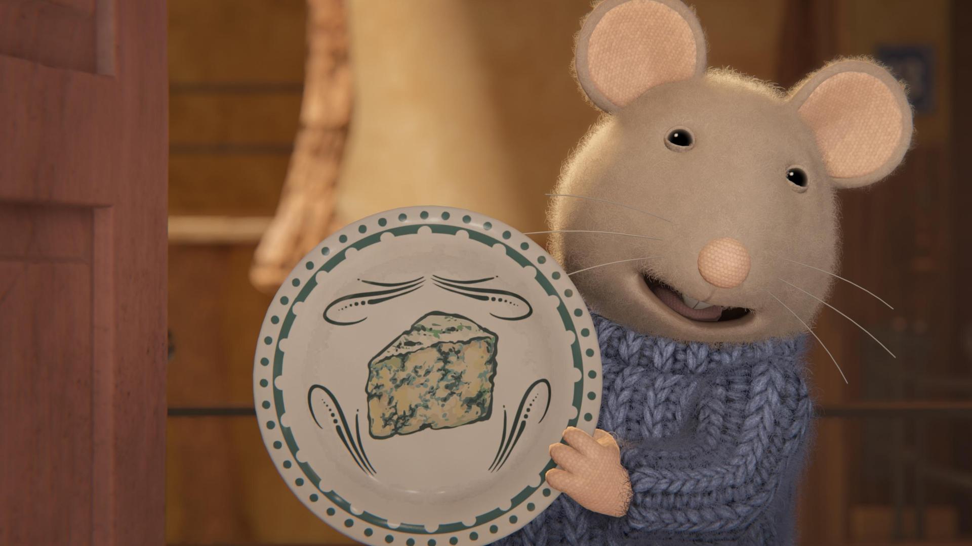 Sam freut sich und hält einen bemalten Teller hoch, auf dem ein Schimmelkäse, ein sogenannter Roquefort, abgebildet ist.