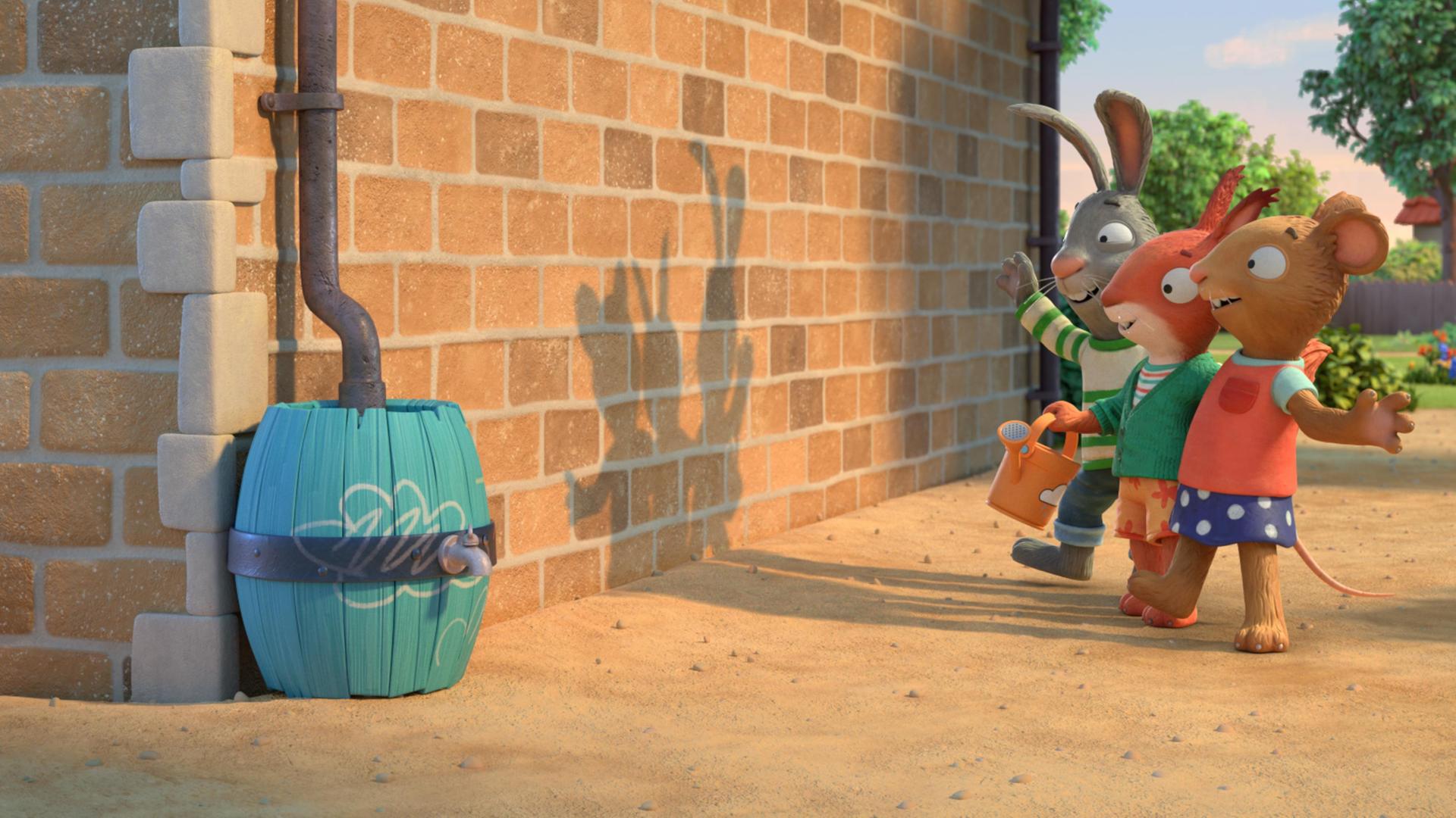 In einer Wohngegend auf einem Weg vor einer Backsteinwand stehen die drei Freunde Pip, das Kaninchen, Posy, die Maus und Jamila, das Eichhörnchen Arm in Arm in einer Reihe und blicken auf den lustigen Schatten, der so durch das von hinten auftretende Sonnenlicht auf der Wand produziert wird.