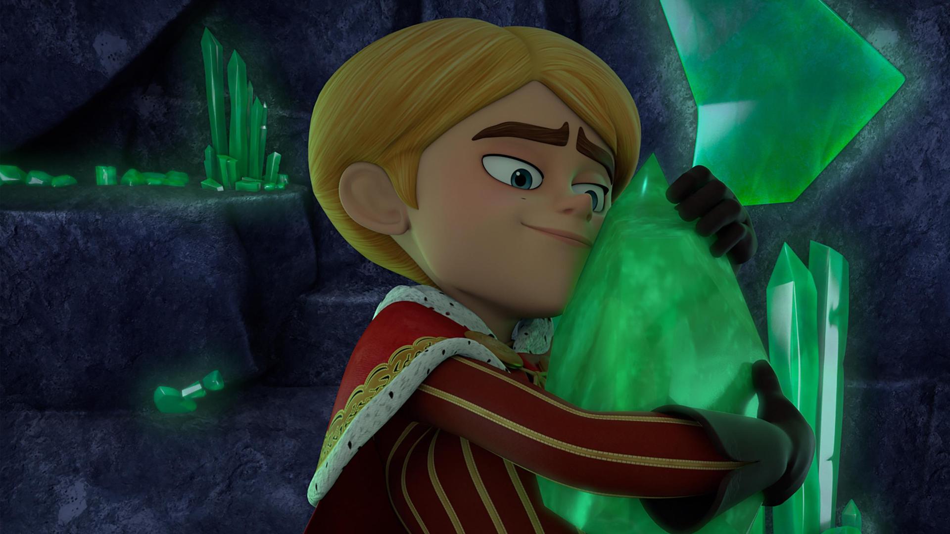 In einer dunklen, felsigen Höhle hält Prinz John fast zärtlich einen großen, grün schimmernden Smaragd in seinen Händen und presst ihn an seinen Oberkörper. Dabei lächelt er glücklich. Um ihn herum sind viele dieser Smaragdkristalle in unterschiedlichen Formen und Größen.