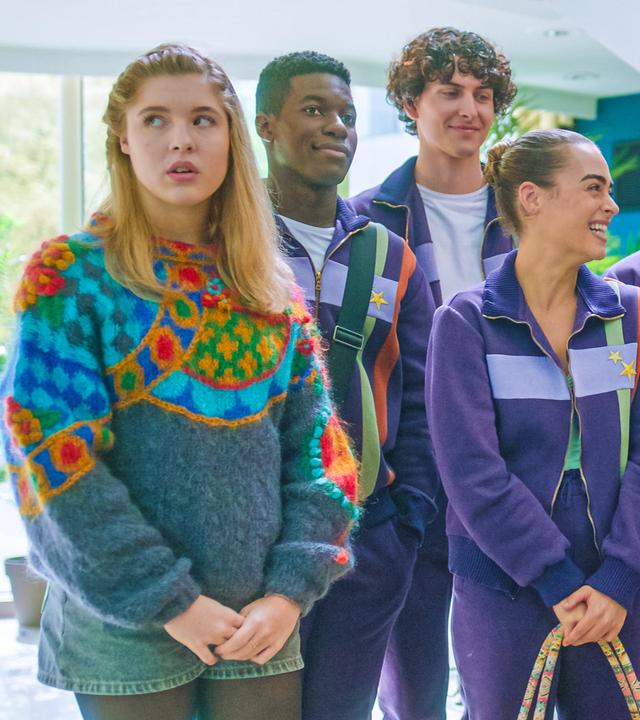 In ihren lilafarbenen Trainingsanzügen steht die Tanzgruppe beisammen und freut sich über Simone, die in der Mitte steht, und Cece freudestrahlend anblickt. Jack, Benoit, Finn und Mia freuen sich mit ihr. Nur Jade steht am Rand der Gruppe und blickt genervt in die andere Richtung. Sie trägt kurze Jeans und einen bunten Pullover.