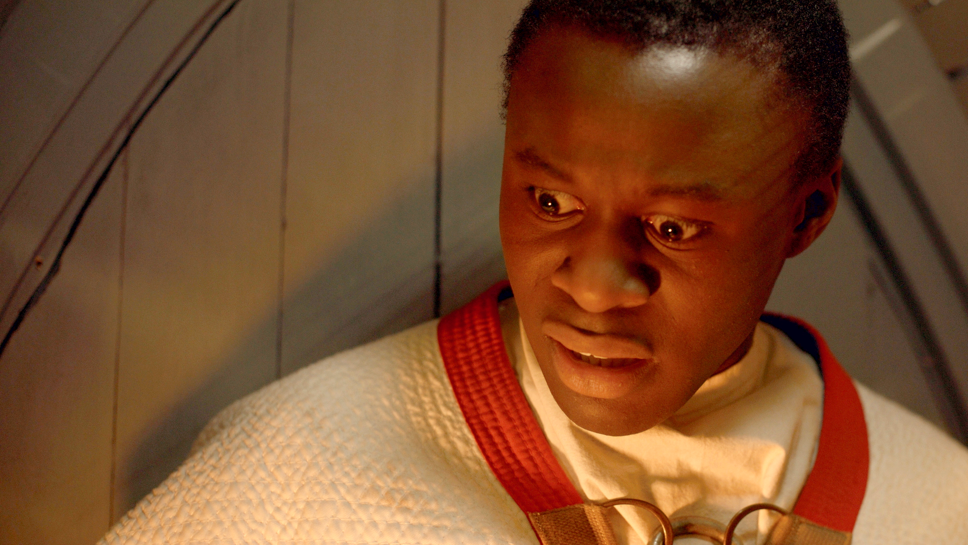 Will ist eingesperrt in einem Holz-Schrein und schaut entsetzt nach unten in die Flammen, die anscheinend unter ihm lodern.