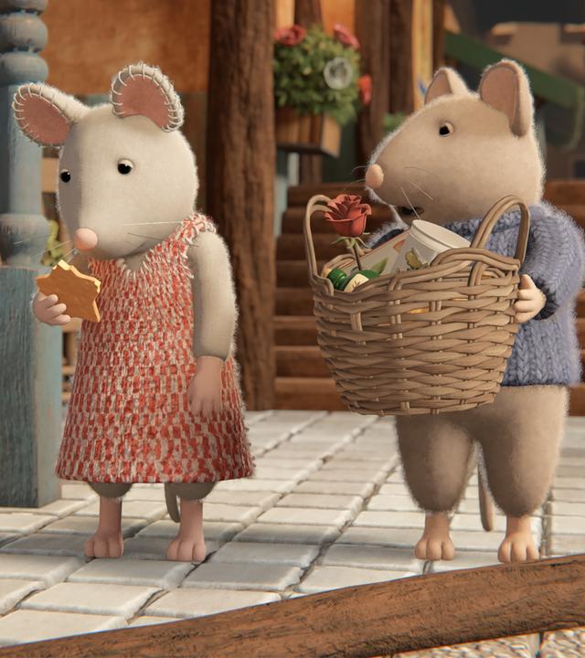 Julia schaut schuldbewusst auf den Käsestern in ihrer rechten Hand, dem eine kleine Ecke fehlt. Sam steht neben ihr und hat einen großen geflochtenen Korb in den Händen. Er sieht irritiert zu Julia. Die beiden stehen im Eingangsbereich des Mäusehauses. Links sind Topfpflanzen, im Hintergrund Holztreppen zu sehen.