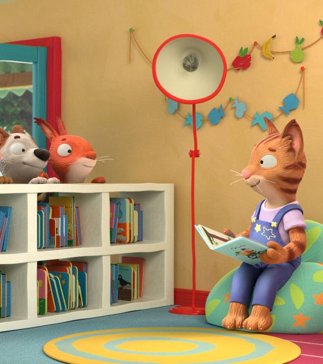 Die Katze Frankie sitzt mit einem aufgeschlagenen Buch auf einem Sitzsack und blickt zu ihren Freunden, die in einer Reihe hinter einem offenen Bücherregal stehen und sie aufmerksam und wissbegierig anblicken. Pip, das Kaninchen, Posy, die Maus, Zac, der Hund und Jamila, das Eichhörnchen.