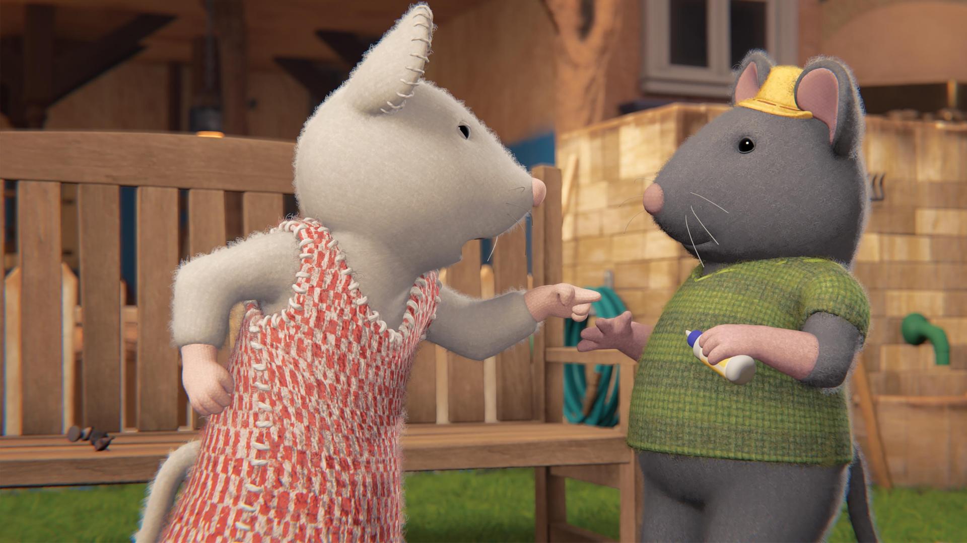 Julia steht vor Tonio, spricht zu ihm und deutet mit ihrem linken Zeigefinger auf ihn. Die beiden stehen im Garten vor einer Parkbank. Im Hintergrund ist die Fassade des Mäusehauses zu sehen.