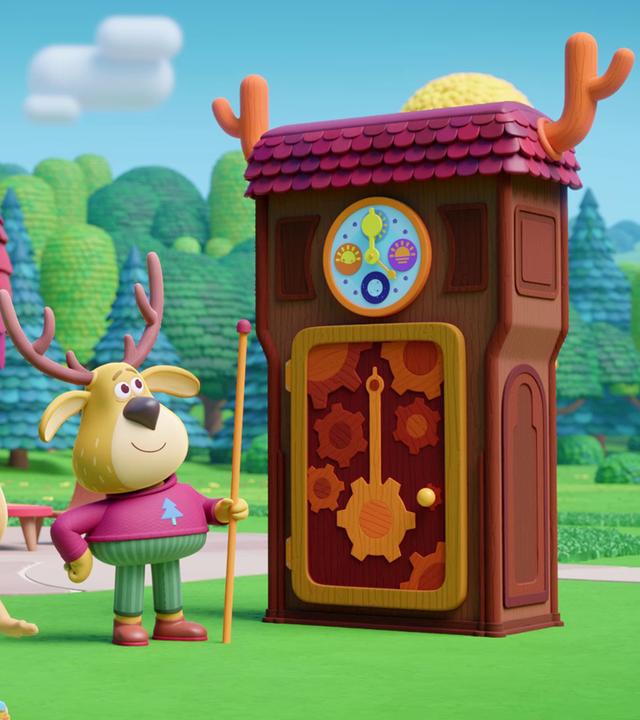 Der Hirsch Fred steht mit einem langen Zeigestock vor einer sehr großen Standuhr mit Geweih. Fred zeigt die Uhr den Kindern Rebecca und Kris.