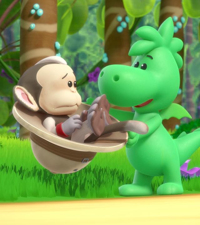 Grisu, der kleine Drache, hält einen Tropenhelm in den Händen. In diesem Tropenhelm sitzt ein traurig blickender Affe. Um sie herum ist ein grüner Urwald.