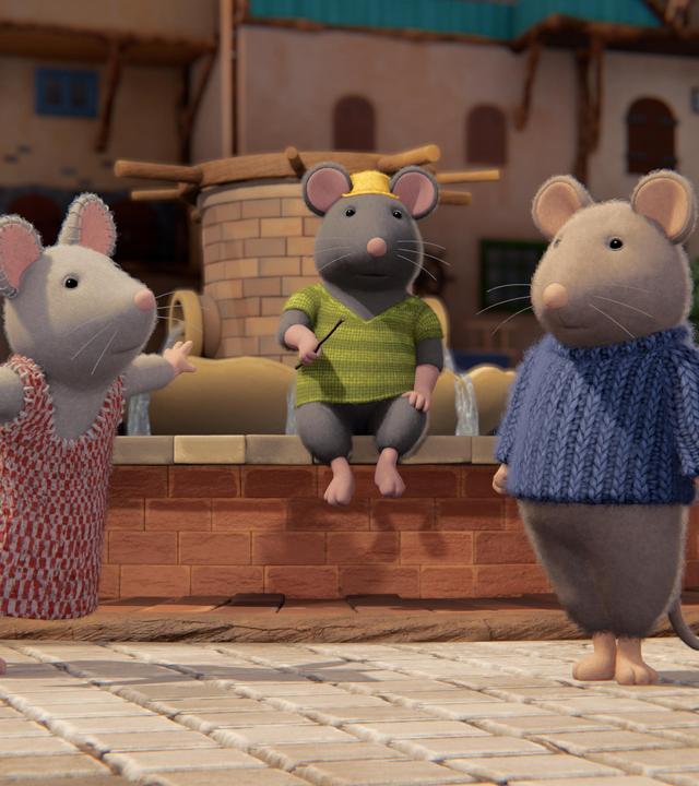 Tonio sitzt regungslos auf dem Brunnenrand im Hof des Mäusehauses. Er hält einen Stab in der rechten Hand. Julia und Sam stehen seitlich vor ihm und schauen erstaunt zu ihm hoch.