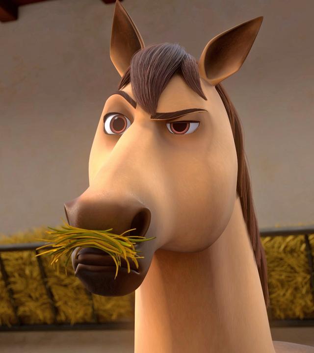 D'Artagnans Pferd Planchet, ein Falbe mit schwarzer Mähne, steht in seiner Box und frisst Heu. Er schaut skeptisch nach vorne.