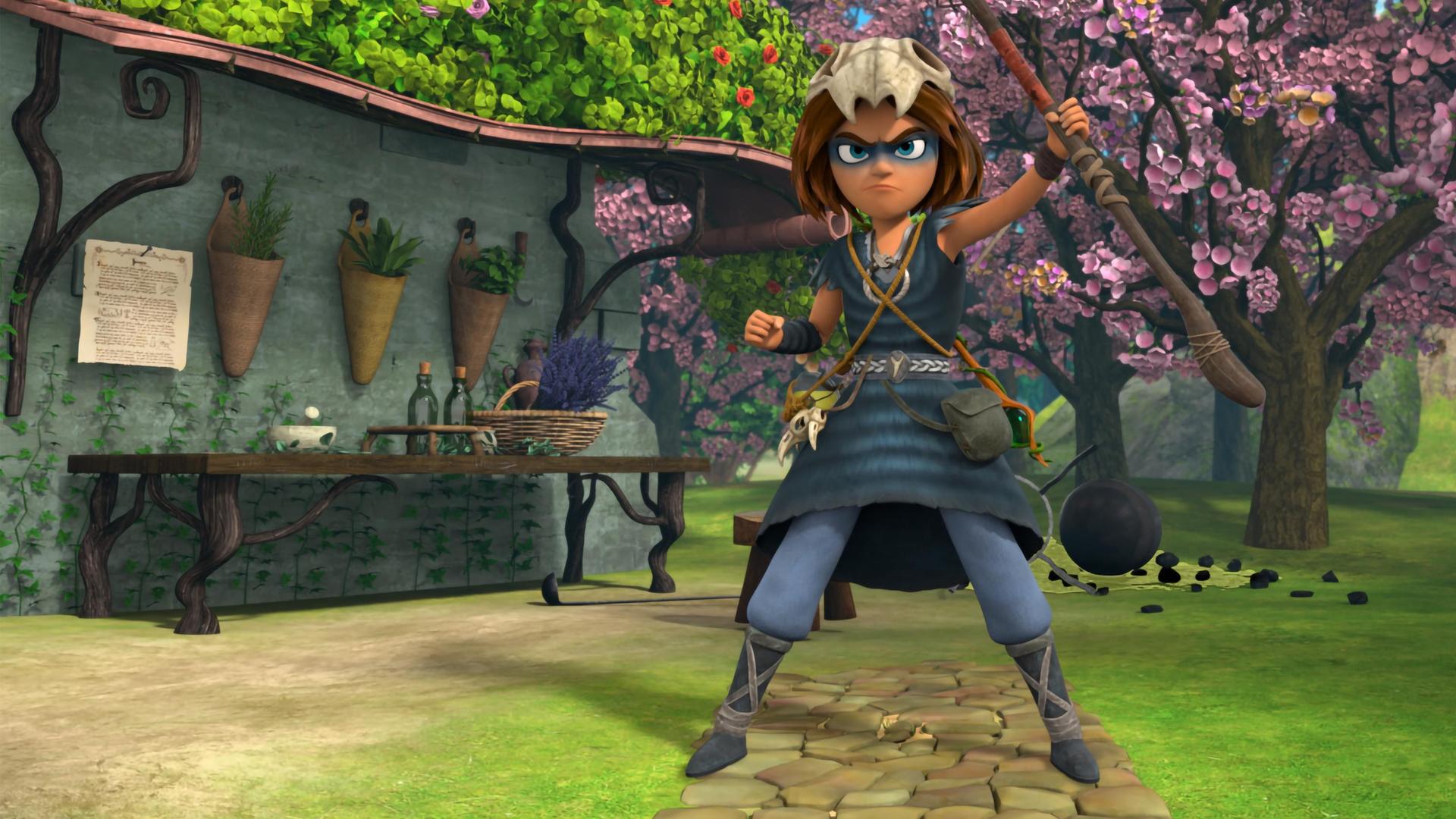 Auf einem gepflasterten Weg im erblühten Garten vor Katells Haus steht der Schamanenjunge Stig. Seinen Druidenstab hält er mutig und stolz nach oben und sein Blick ist entschlossen.