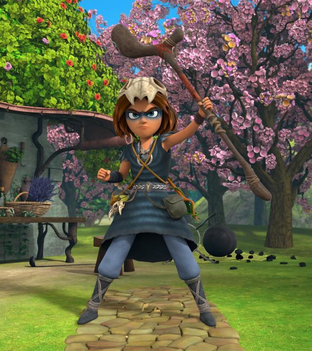 Auf einem gepflasterten Weg im erblühten Garten vor Katells Haus steht der Schamanenjunge Stig. Seinen Druidenstab hält er mutig und stolz nach oben und sein Blick ist entschlossen.